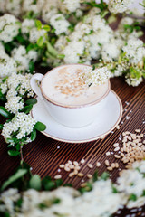 Coffee in hand and white flowers.