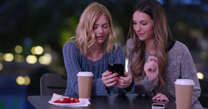 Lovely blonde girl socializing with friend and sharing smartphone pictures outdoors in Paris, France, Two cute girls using cell phone to look at pictures In French pavilion, 4k