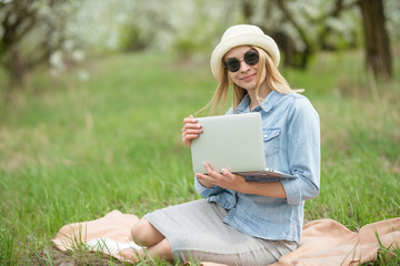 Girl with a smile with a laptop outdoors. The concept of freelancing and work in nature