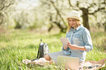 Girl with a smile with a tablet in her hands in nature. The concept of freelancing and work in nature