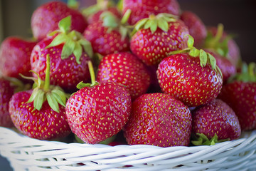 Ripe strawberries in white basket  on  gray background.
