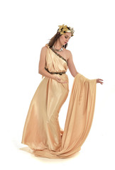 full length portrait of brunette woman wearing long golden grecian gown, standing pose. isolated on white studio background.