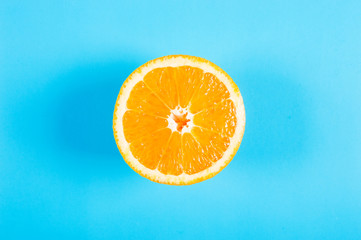 Top view of a half orange fruit on blue colored background