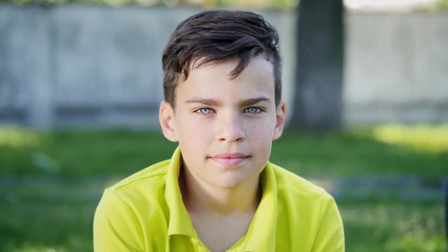 Looking into the camera boy with blue eyes. Cute ten year old boy with blue eyes looking at camera slow motion in nature