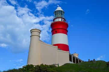 Fototapeta na wymiar Beautiful lighthouse. Red and white lighthouse, view from bottom, blue sky with clouds on background
