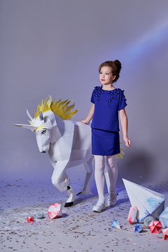 Pretty child elegant blue dress for teenager,walking,looking side.Beautiful little lady girl and fabulous unicorn near.Fashion style kid.Designer collection.Studio, lilac background.full-length.