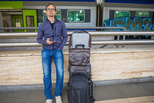 Man with suitcases waiting train on platform of railway station in Rimini in Italy