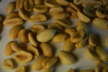 On white glass plate are peanut nuts with salt fried in yellow earth-nut, groundnut, goober, monkeynut