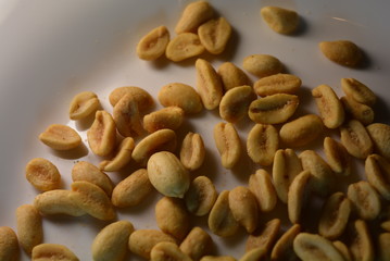 On white glass plate are peanut nuts with salt fried in yellow earth-nut, groundnut, goober, monkeynut