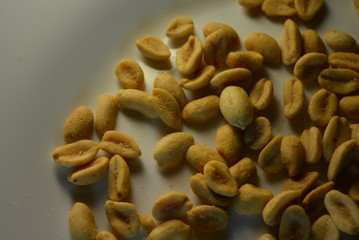 On white glass plate are peanut nuts with salt fried in yellow earth-nut, groundnut, goober, monkeynut