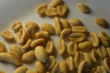 On white glass plate are peanut nuts with salt fried in yellow earth-nut, groundnut, goober, monkeynut