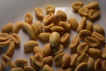 white glass plate are peanut nuts with salt fried in yellow earth-nut, groundnut, goober, monkeynut