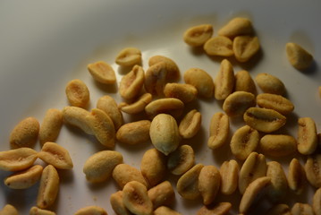 On white glass plate are peanut nuts with salt fried in yellow earth-nut, groundnut, goober, monkeynut