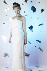 A young girl in the image of the snow Queen on a blue background with ice