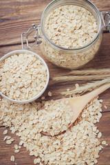 Oatmeal or oat flakes in bowl on wooden table. Toned.