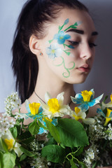 Portrait of a young girl with flowers and face art in the form of flowers on her face