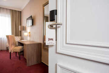 opened doors with label do not disturb in hotel room
