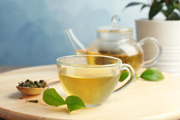 Cup of hot aromatic tea and teapot on table