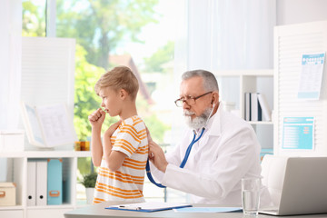 Doctor examining coughing little boy at clinic