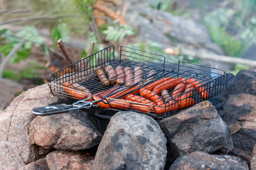 Sausage fire-roasted on the grill. Picnic in nature
