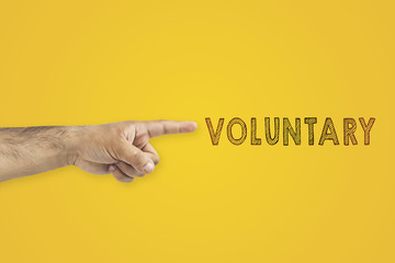 voluntary concept. A man's pointing hand next to the inscription: voluntary on yellow background