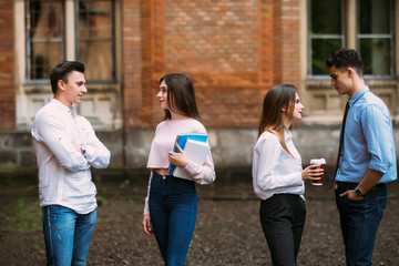Obraz premium Students in campus communicating, laughing. Group of college friends showing positive emotions, holding books.