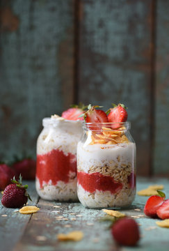 Healthy nutritious gluten free breakfast. Overnight oats with organic strawberry and cornflakes in glass jars on shabby blue background copyspace
