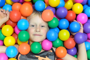 The boy lies, buried in the colorful balls of the game room.