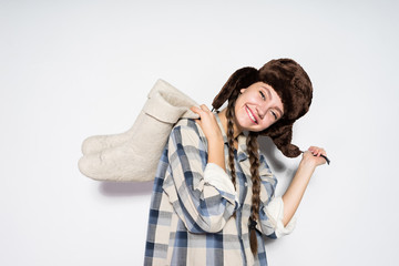 laughing Russian girl in a fur hat holds gray winter boots