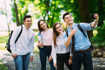 Group of teenager students doing selfie over the university building. Four young happy student making selfie and smiling outdoors.
