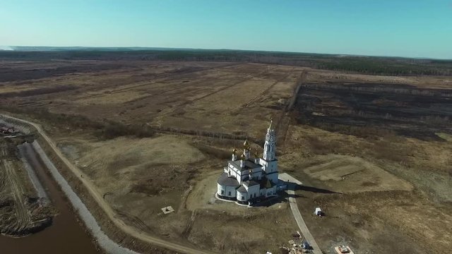 Old church on river bank. Footage. Aerial view. Cherch in the empty field