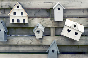 Wooden bird houses with heart shaped holes on a wooden fence      