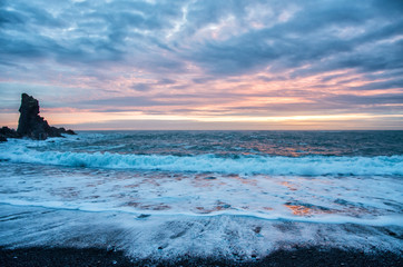 Obraz premium Amazing sunset at black beach in Iceland, cloudy colourful sky, rocks in the ocean