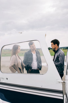 Young Male Pilot Taking to Caucasian Couple in Front of Small Ch