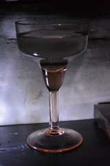 Glass glass on a leg of yellow glass for champagne and martini on a black table with back light