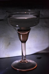 Glass glass on a leg of yellow glass for champagne and martini on a black table with back light