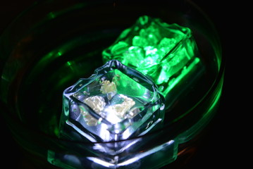 In a glass glass from under the champagne floats a green ice cube and a white ice cube is very stylish and beautiful
