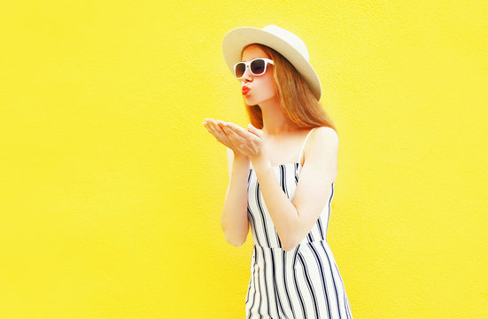 Fashion woman in profile sends an air kiss on colorful yellow background