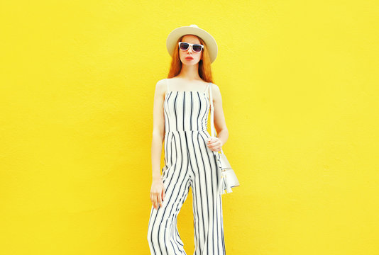 Fashion woman is wearing a white striped pants, round hat on colorful yellow background