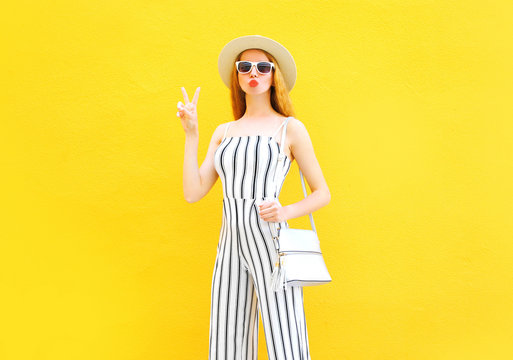Fashion young woman is wearing a white striped pants, round hat on colorful yellow background