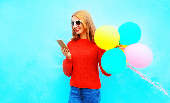Stylish fummy girl is using smartphone with an air balloons on blue background