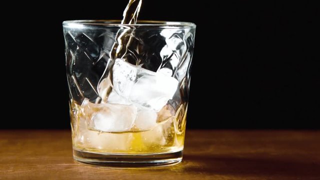 Whisky is poured into glass in slow motion