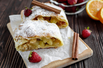 Homemade strudel with apples on a wooden background