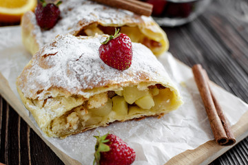 Homemade strudel with apples on a wooden background