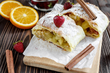 Homemade strudel with apples on a wooden background