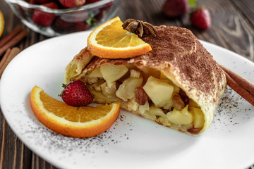 Homemade strudel with apples on a wooden background