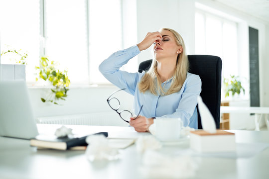 Young businesswoman suffering flu at work