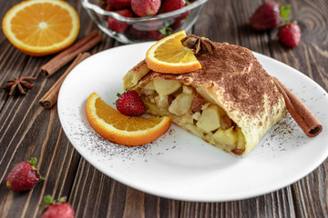 Homemade strudel with apples on a wooden background