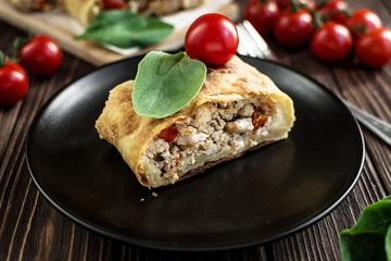 Homemade strudel with meat on a wooden background