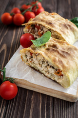 Homemade strudel with meat on a wooden background